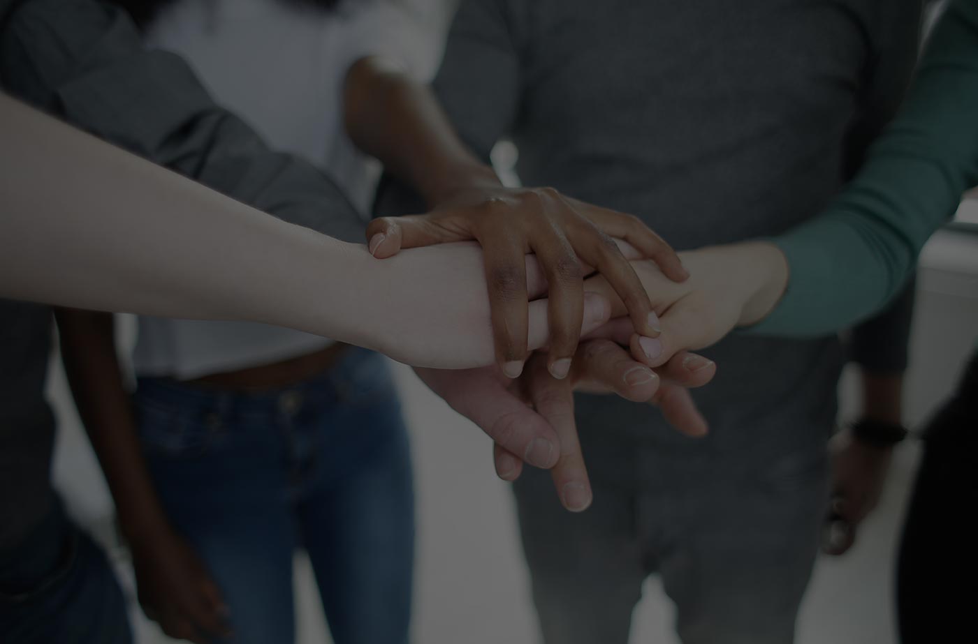 Racially diverse group of people stacking hands together